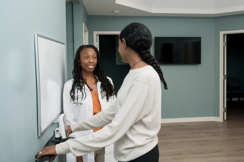 A patient stepping onto the body composition scale with Doctor Angela Lipscomb-Hudson