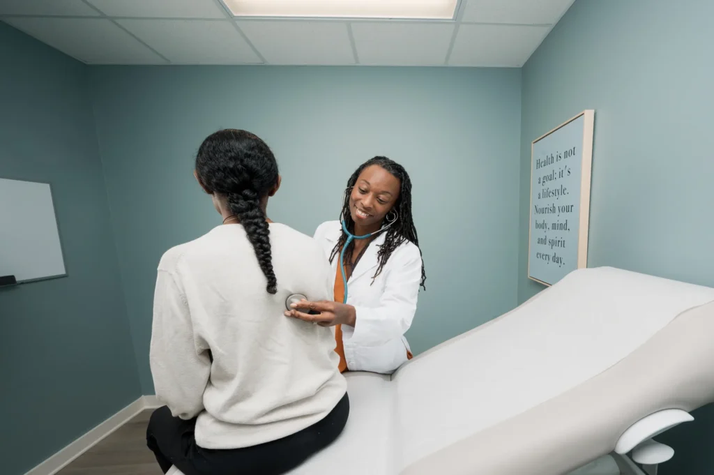 Doctor Angela Lipscomb-Hudson listening to a patient's lungs with a stethoscope during a physical examination